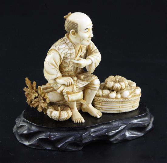 A Japanese ivory okimono of a farmer smoking a pipe, early 20th century, height 9cm, ebonised wood stand